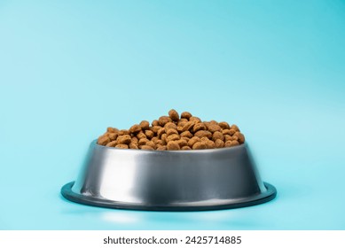 Brown cat or dog kibble in a metal bowl isolated top view close-up. Nutritious healthy diet pet food scattered around, falls and cascades the bowl. Dry cat or dog food spills from a bowl. - Powered by Shutterstock