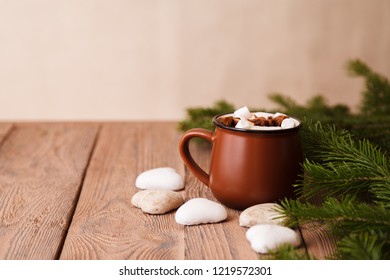 Brown ceramic mug of traditional hot drink with marshmallow and star anise, in Christmas atmosphere with Christmas branches and cones on wooden background. Close-up, top view, copy space - Shutterstock ID 1219572301