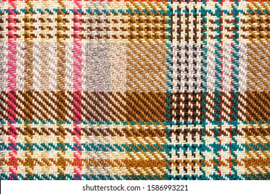 Brown checkered fabric with colored threads. Scottish wool. Fabric for plaid coat and suit. Close-up. Background