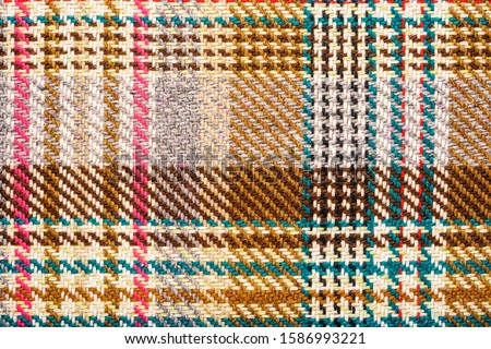 Brown checkered fabric with colored threads. Scottish wool. Fabric for plaid coat and suit. Close-up. Background