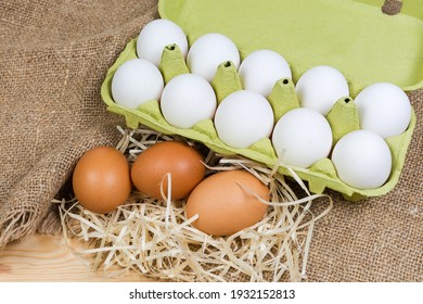 Brown Chicken Eggs On A Wood Shavings And White Eggs In Carton Made Of Recycled Paper Pulp On A Sackcloth Close-up  
