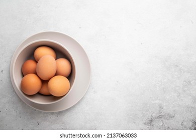 Brown chicken eggs in plate on light background. Concept farm products and natural nutrition. Top view, copy space or empty place for text.