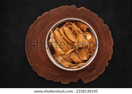 brown Chinese stewed calf of duck leg in ceramic bowl serve on natural wood on dark tone texture background, top view, flat lay, Thai food, Ped Pa Lo, Ped Palo, Ped Palow