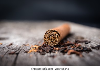brown cigar  with tobacco leaves on grey wooden table