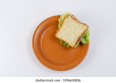 Brown Clay Plate And Chopped Ham Sandwich On White Background. Square Sandwiches With Ham, Tomato, Lettuce, Dill, Sauce. Ready To Eat Healthy Food. Top View.