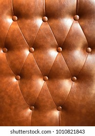 Brown Cognac Leather Pattern With Button. Leather Sofa Backrest With Button Decor. Backrest Background From Leather Sofa.