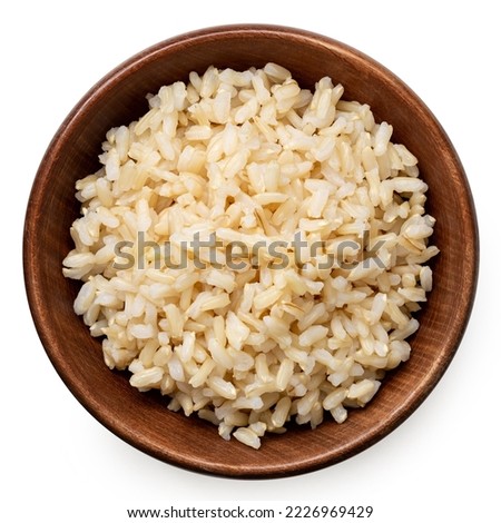 Brown cooked rice in a brown wood bowl isolated on white. Top view.