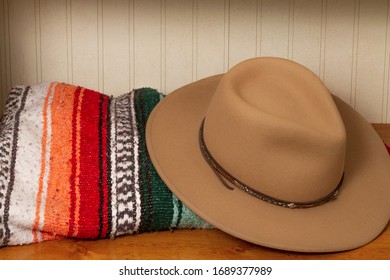 Brown Cowboy Hat With Colorful Mexican Blanket On A Wooden Table