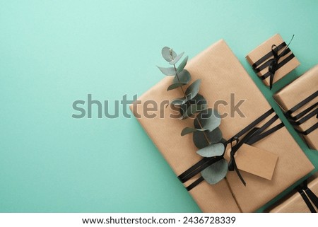 Brown craft gift boxes with black ribbons and Eucalyptus on mint background. Space for your text.