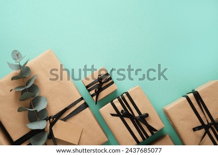 Brown craft gift boxes with black ribbons and Eucalyptus on mint background. Space for your text.