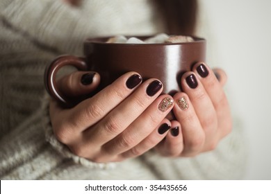 Brown cup with cocoa and marshmallow in the hands of the girl. Manicure gel nail.
