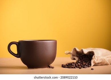 brown cup with coffee and raffia sack with roasted coffee beans, with yellow background - Powered by Shutterstock