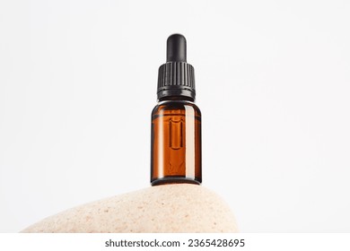 Brown dropper bottle without label is on light stone. - Shutterstock ID 2365428695