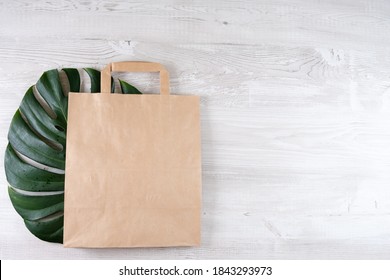 Brown Eco Bag On A White Wooden Table. Packaging For Your Products, Free Space For A Logo