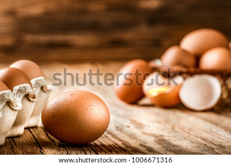 Brown eggs in carton box. Broken egg with yolk in background. 
