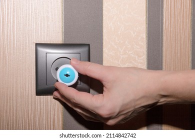 Brown Electrical Outlet On A Brown Tone Wall And A Woman's Hand Inserting A Plug, Child Proof. High Quality Photo