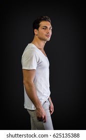 Brown Eyed, Black Haired Latin Man Standing In Studio, Looking At Camera, Isolated On Black Background, Profile View