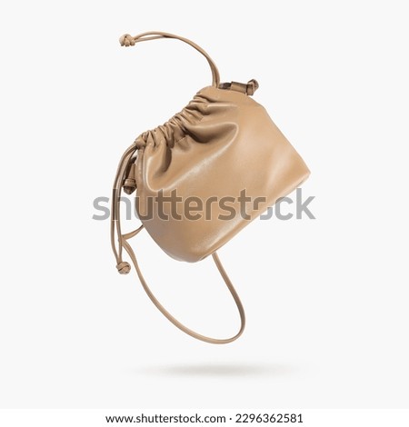 A brown female handbag with straps flying on a gray background. Minimalistic layout with bag. Advertising for ladies store, blog. Trendy women's accessories. Copy space. Objects for design, Mock up.