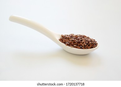 Brown Flax seeds or Linseeds or Common flax in the white spoon isolated on white background. Flax seeds are rich of omega fat.