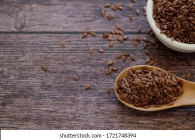 Brown Flax seeds or Linseeds or Common flax in the white bowl and wooden spoon and on wooden table background. Flax seeds are rich of omega fat.