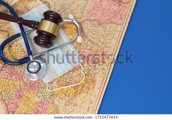 brown gavel and a\
medical stethoscope and a protective mask on a geographical map.\
symbol photo for bungling and medical error. Concept stay home and\
remote work.