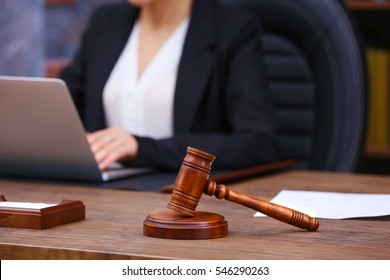 Brown gavel on wooden table and female lawyer on background, close up view