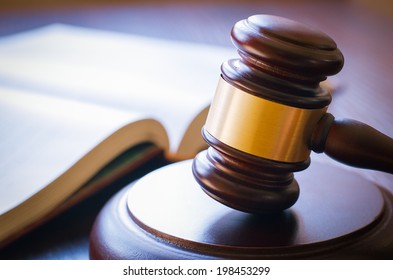 brown gavel and open book on a wooden table of the law in the courtroom