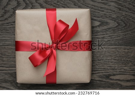 brown gift box with red bow on wood table, top view