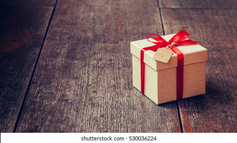 Brown gift box and red ribbon with tag on wood background with space. Vintage gift box on wooden board with space for text. - Powered by Shutterstock