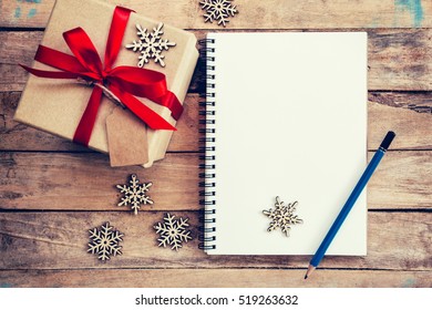 Brown gift box, snowflakes and notebook on wood table for christmas and new year concept. - Powered by Shutterstock