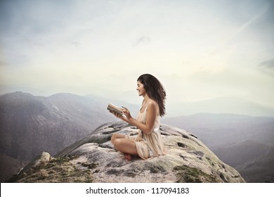 Brown Girl Reading A Book On The Top Of A Mountain