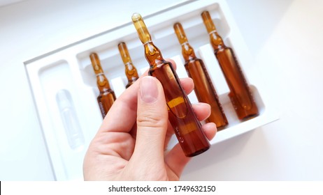 brown glass ampoule with liquid on a female hand close-up on the background of other ampoules - Shutterstock ID 1749632150