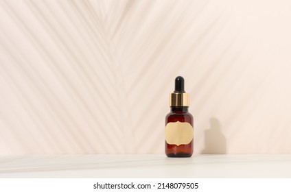 Brown glass bottle with a pipette stands on a brown background. Container for cosmetics, serum and oil, palm leaf shadow