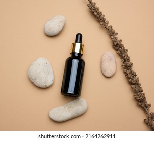 Brown glass bottle with a pipette stands on a brown background. Container for cosmetics, serum and oil, flat lay