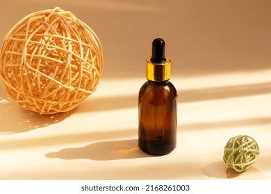 Brown glass dropper bottle with a pipette between two wicker rattan spheres. Organic, natural cosmetics. Beauty, skin care. Spa products. Close up, copy space. Selective focus