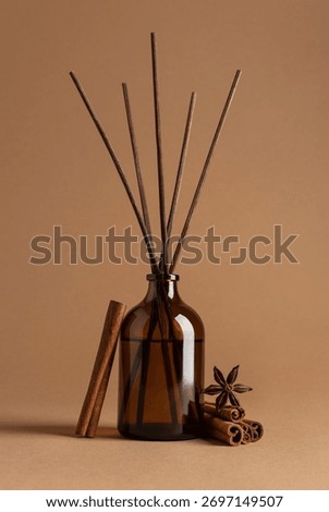 Brown glass reed diffuser with aromatic sticks, cinnamon rolls and star anise spices on brown background. Concept of fragrance, home decor, wellness, spa, relaxation and natural lifestyle.