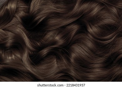 Brown hair close-up as a background. Women's long brown hair. Beautifully styled wavy shiny curls. Hair coloring. Hairdressing procedures, extension. - Shutterstock ID 2218431937