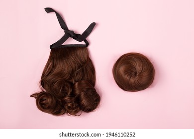 A Brown Hairpieces On The Pink Background. A Ponytail And A Bun Chignon, Hair Extension, Quick Easy Hair Style Concept. Flat-lay, Top View. Copy Space.