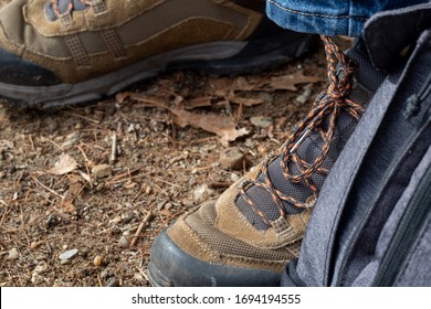 Brown Hiking Boots With Orange And Black Laces With Gray Backpack And The Bottom Of Blue Jeans Showing