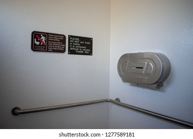 Brown Informational Signs, Metal Roll Toilet Tissue Dispenser, Horizontal Grab Bar In The Public Outdoor Restroom. ADA Compliant Toilet.