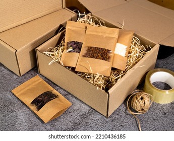 Brown kraft paper doypack bags with groceries on a cardboard box with shavings. Packaging for foods and goods template mock-up. Packs with windows for weight products. - Shutterstock ID 2210436185
