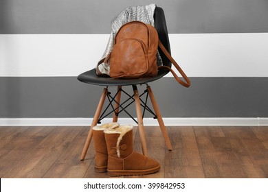 Mochila de cuero marrón y camisas en silla cerca de botas adentro