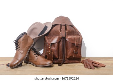 Brown Leather Bag Or Backpack With Brown Shoes,hat ,gloves On Wooden Background
