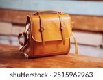 Brown leather bag with a handle and a long strap.