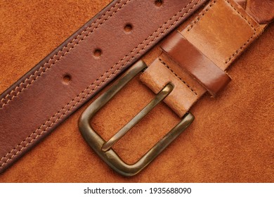 Brown leather belt with bronze buckle on chamois leather background texture. Man fashion concept. Top close up view.