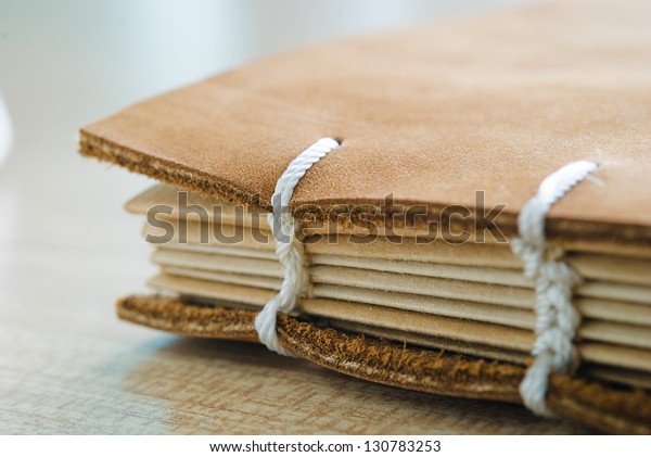 brown\
leather book cover with white thread book\
spine