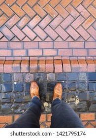 Brown Leather Boots On A Rain Soaked Brick Road Street. 