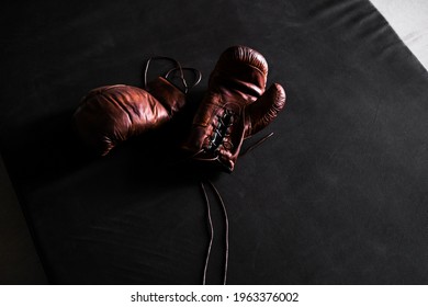 Brown Leather Boxing Gloves On A Training Mat Black Background Top View. Mockup