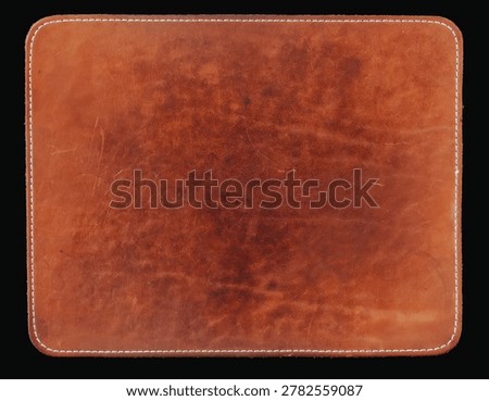 Brown leather computer mouse pad with stitched border, worn surface, rounded corners, isolated on black background. Natural background for office desk, workspace, product mockup featuring mouse pad