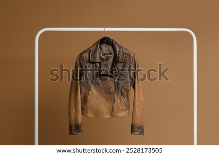 Brown leather jacket with star-shaped stud details, adding a unique and stylish touch to the classic design.